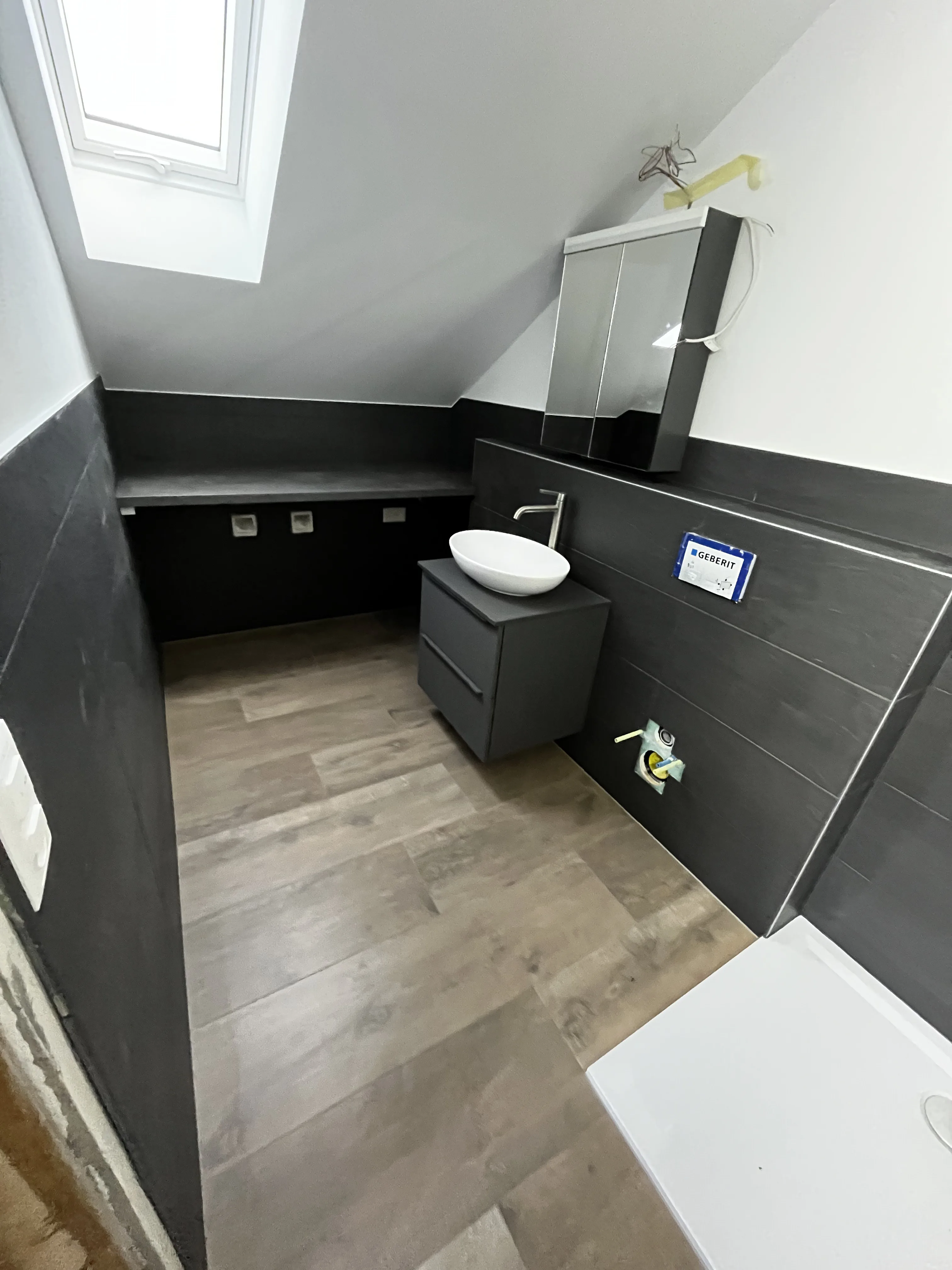 Modernes Badezimmer mit schwarzen Fliesen und Dachfenster