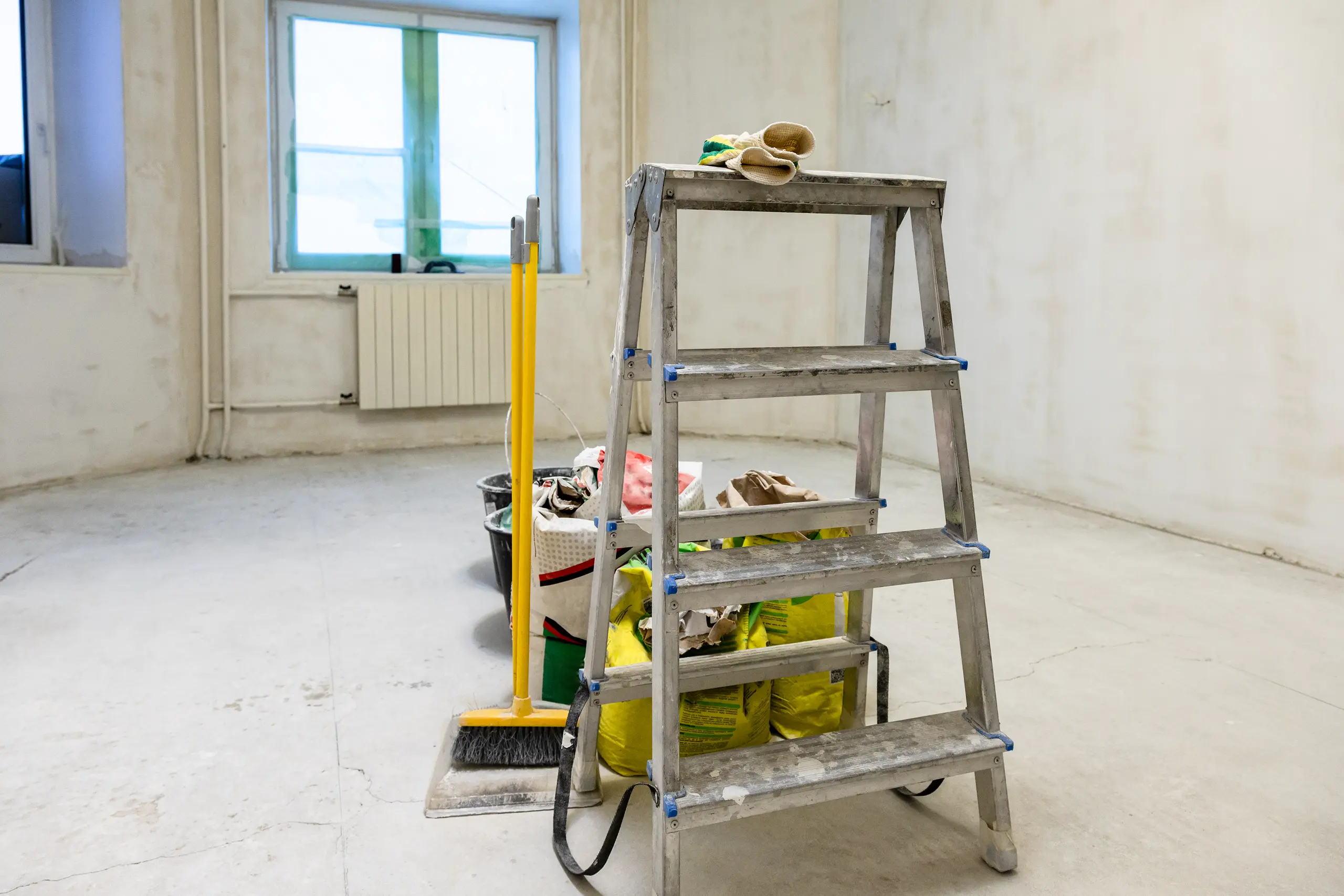 Leitern und Reinigungsmaterialien in einem renovierten Raum