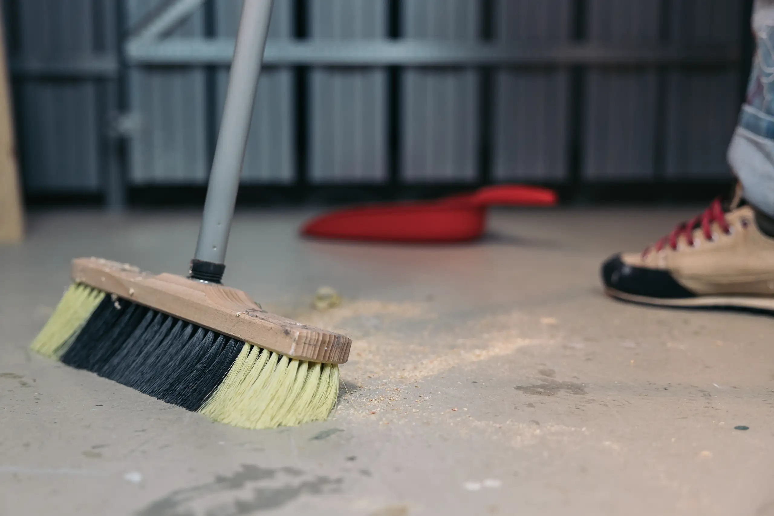 Kehren des Bodens mit einem Besen während der Wohnungsreinigung