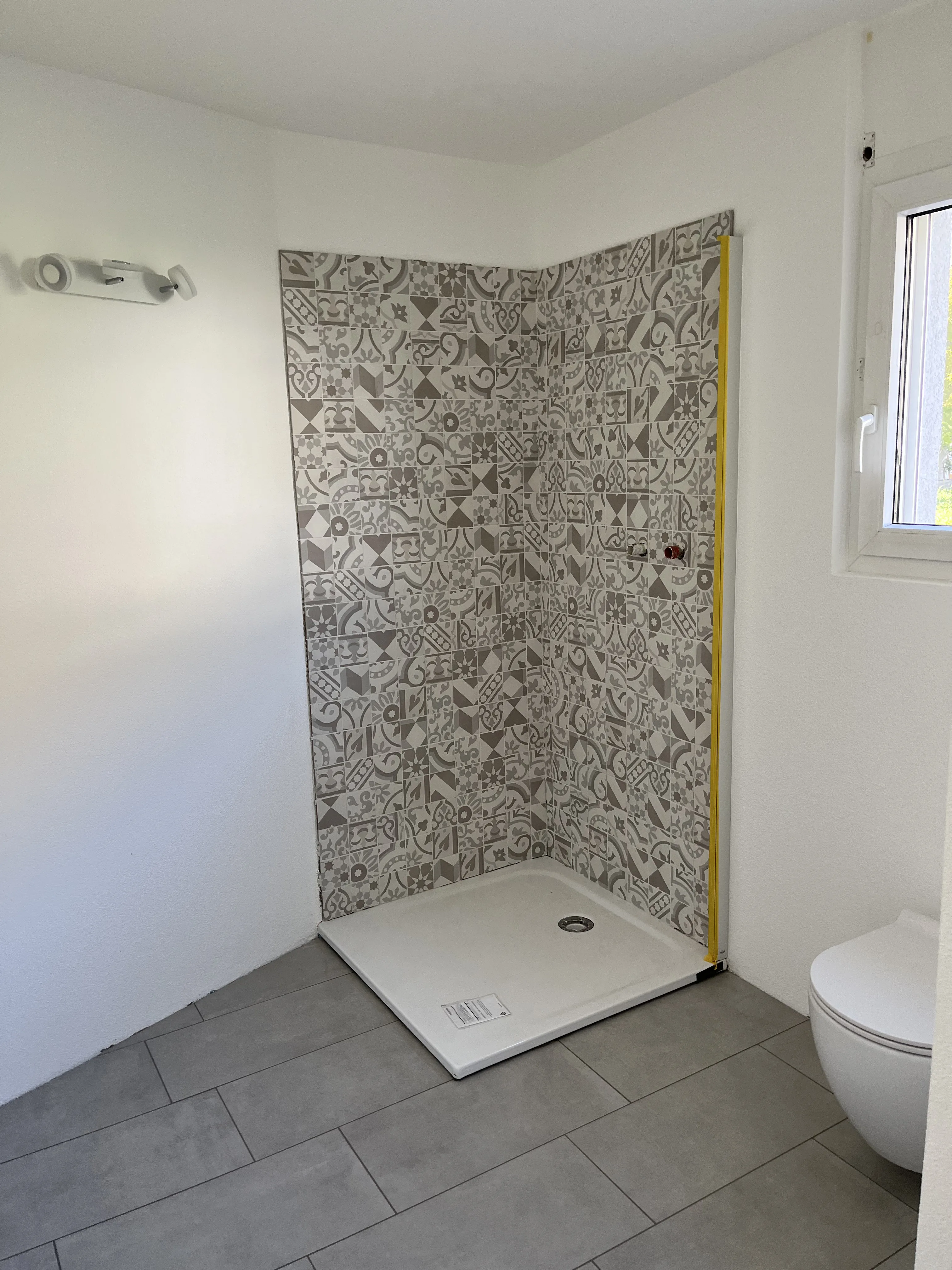 Modernisierte Dusche mit dekorativen Wandfliesen und stilvollem Bodenbelag