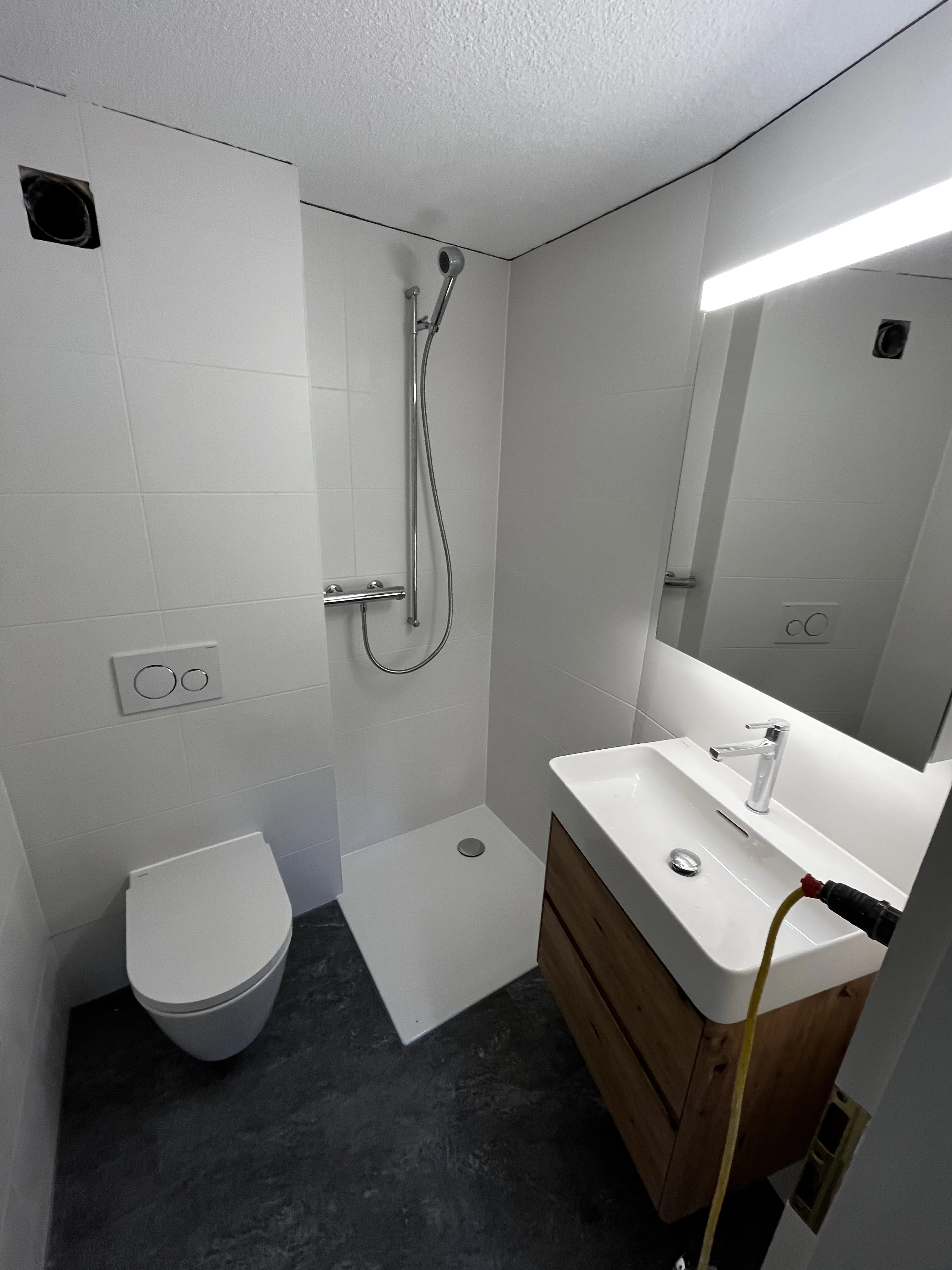 Modernes Badezimmer mit Dusche, Waschbecken und WC in hellem Design