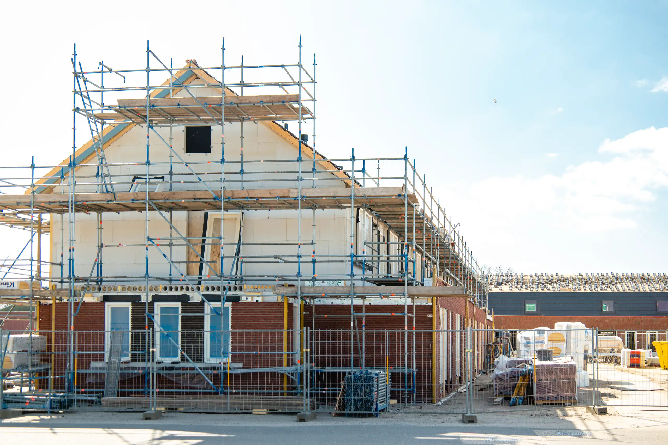 Baustelle mit Gerüst um ein renovierungsbedürftiges Haus, Fokus auf Aussenarbeiten