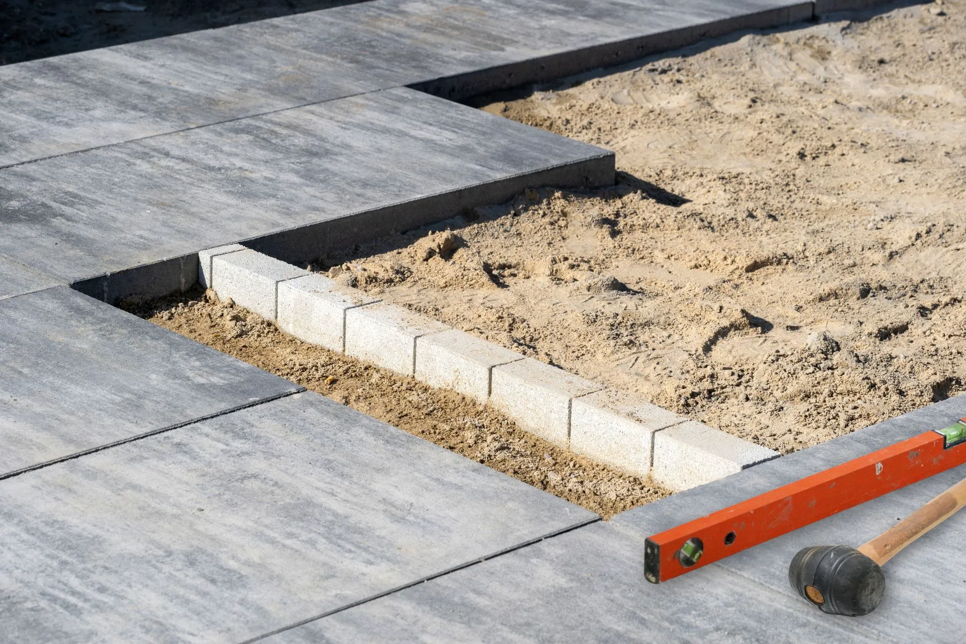 Verlegung von Betonplatten auf einer Baustelle mit Sanduntergrund