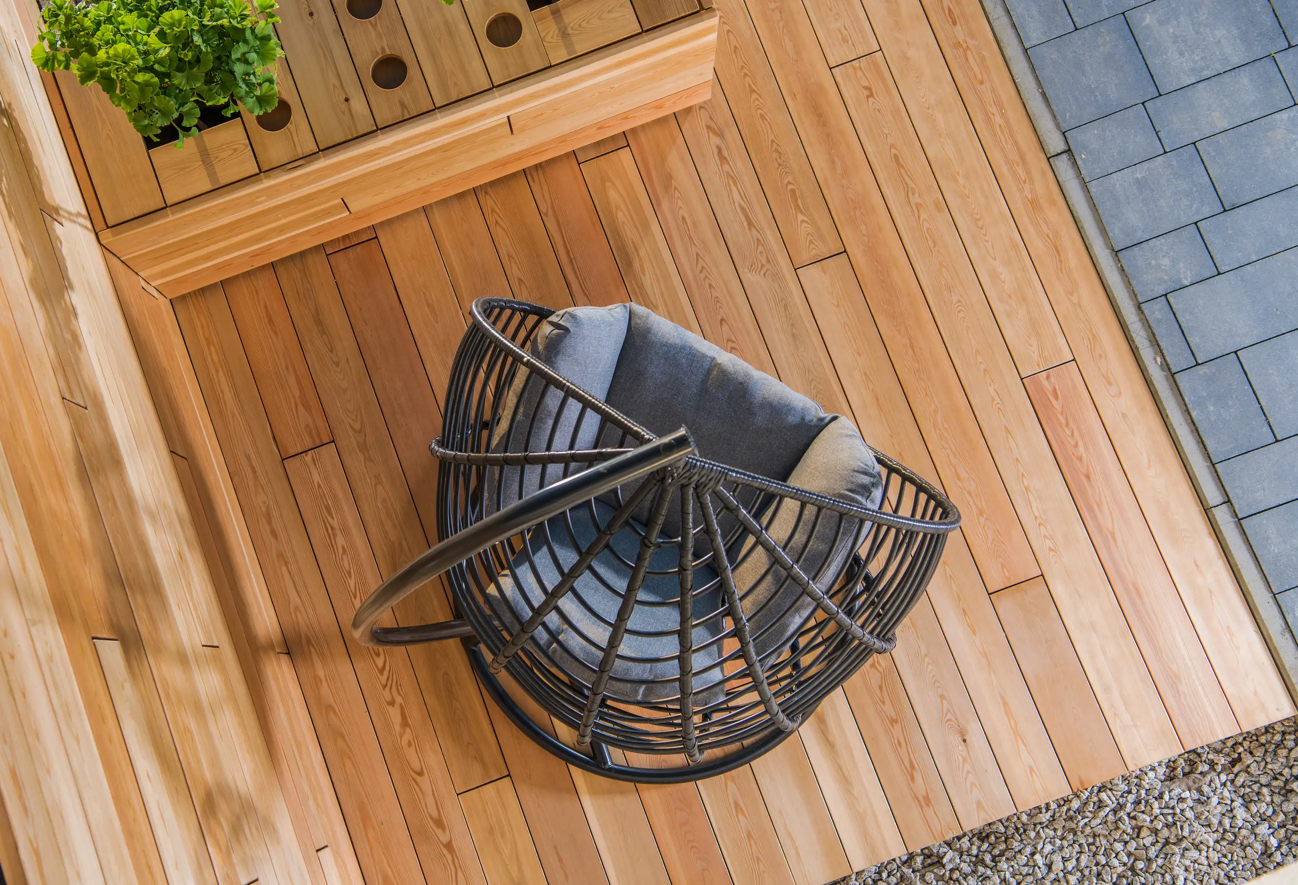 Hängesessel auf einer Holzterrasse mit modernen Fliesen im Hintergrund