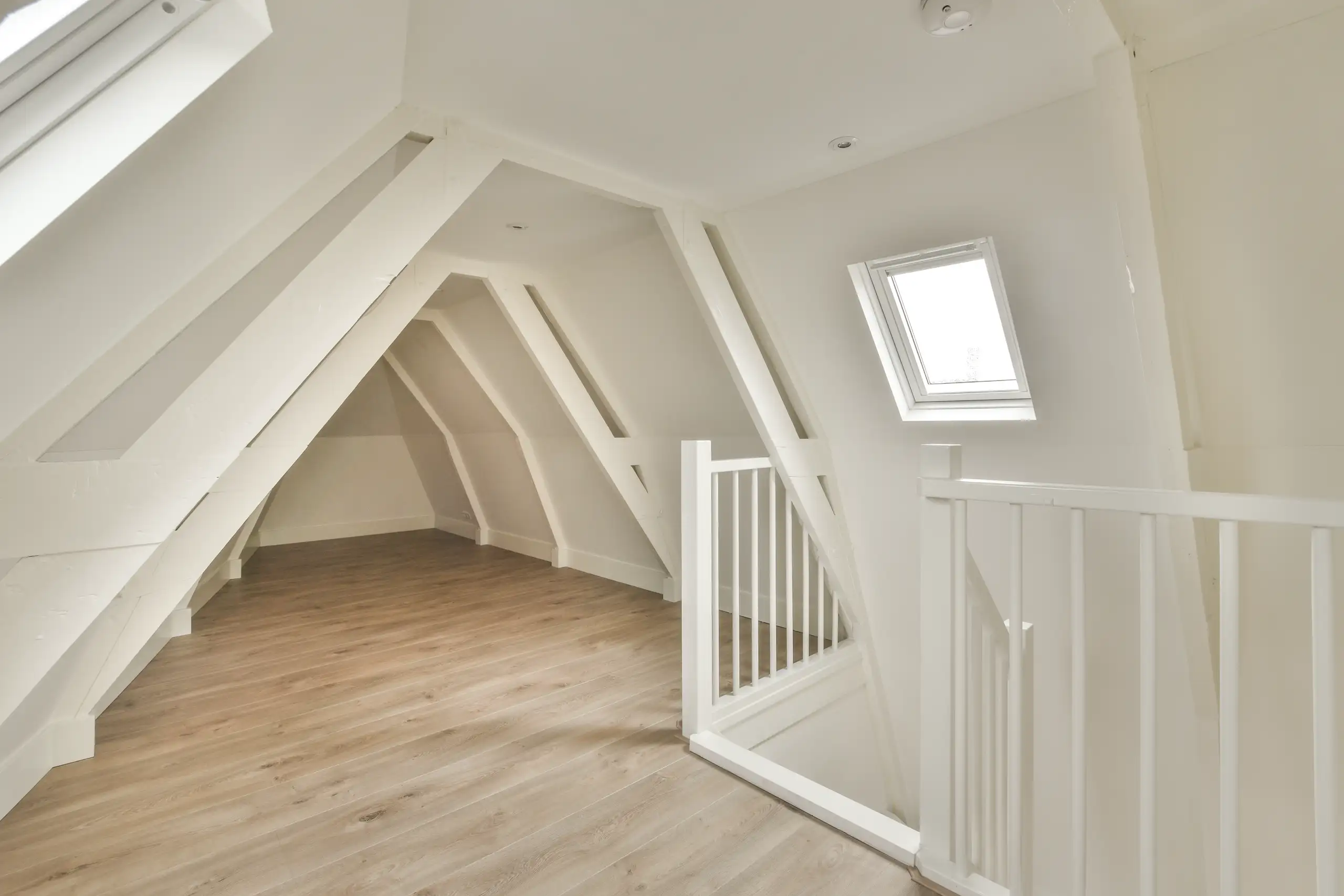Heller Dachboden mit Holzfussboden und weissen Wänden, ideal für Ausbauarbeiten