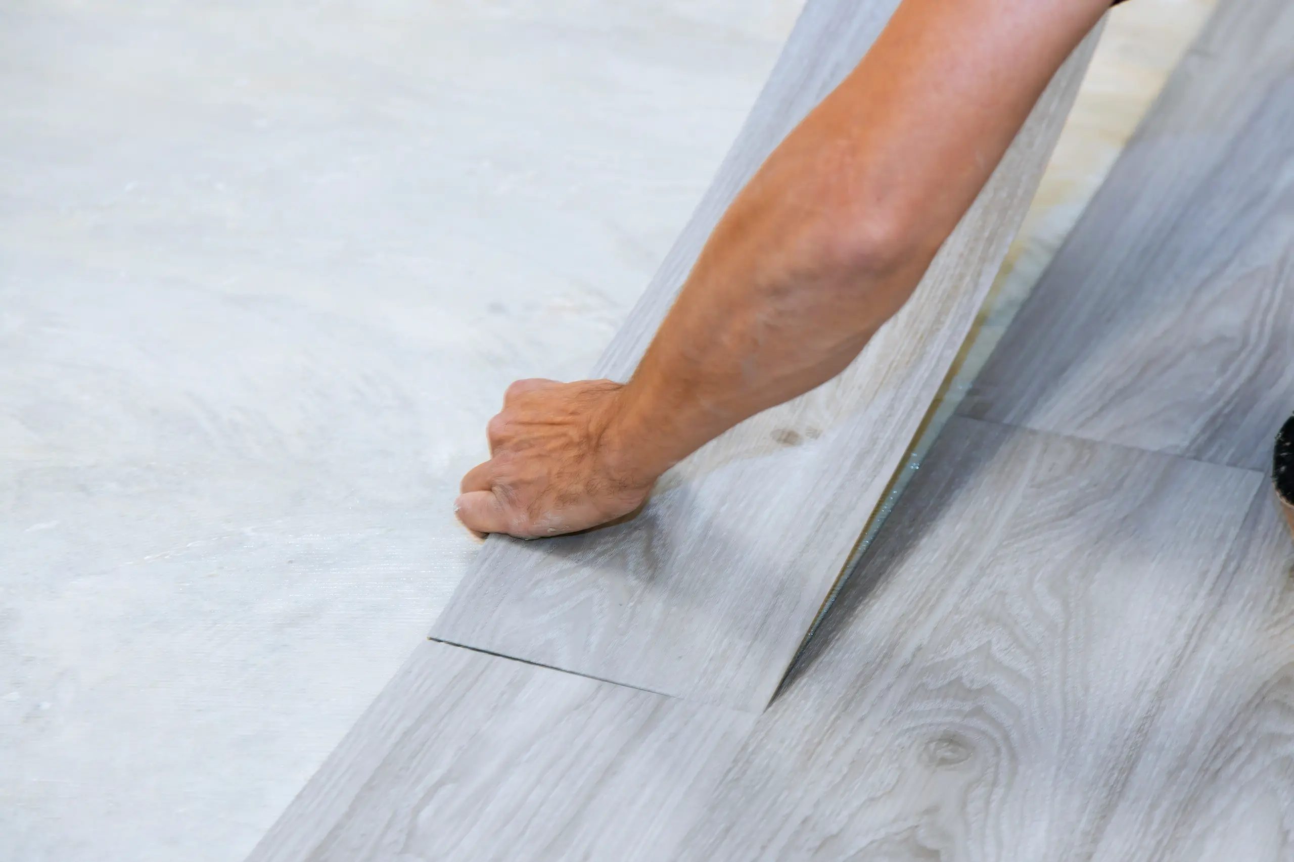 Ein Handwerker verlegt Laminatboden auf einer hellen Unterlage