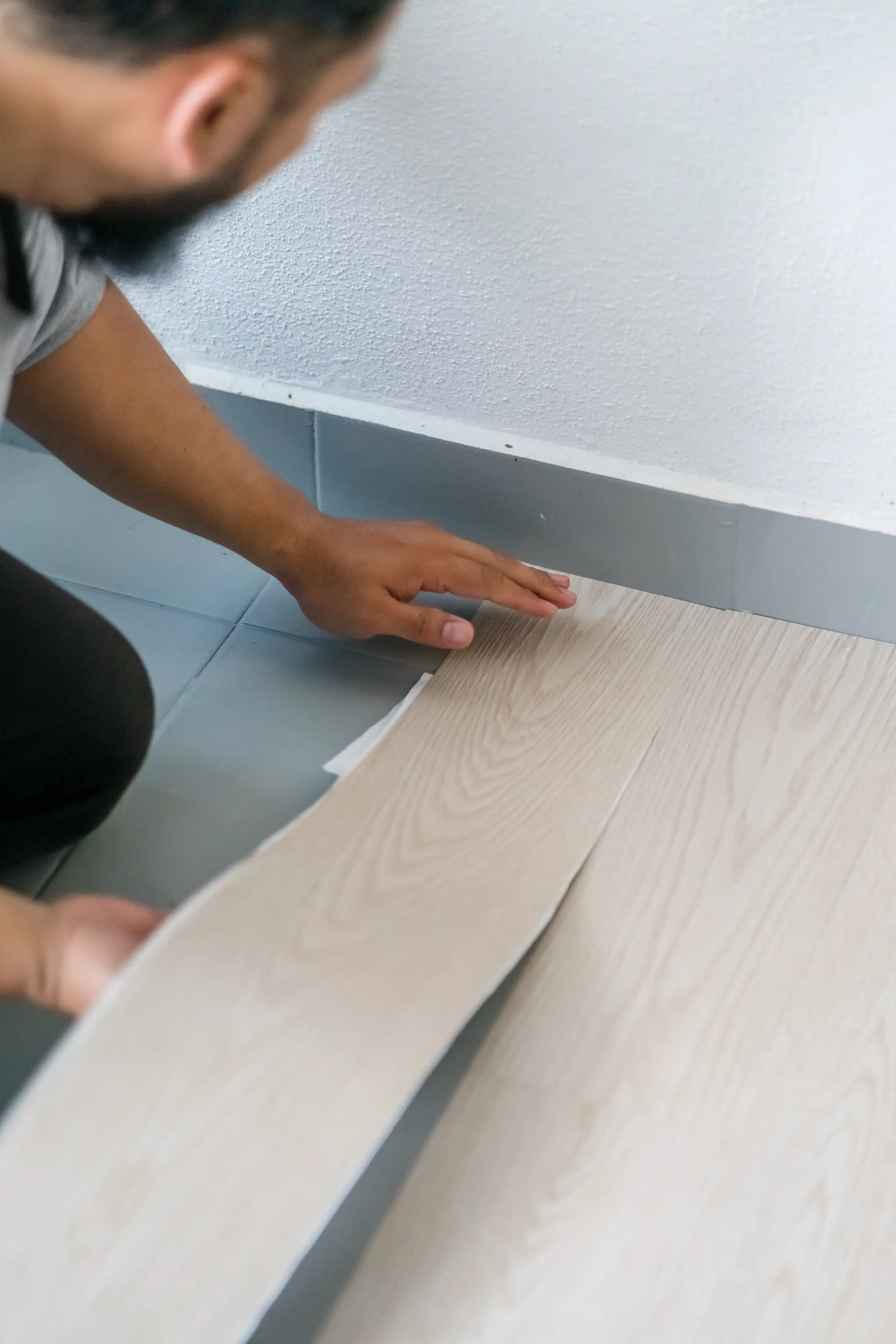 Ein Handwerker verlegt Vinylboden in einem modernen Raum